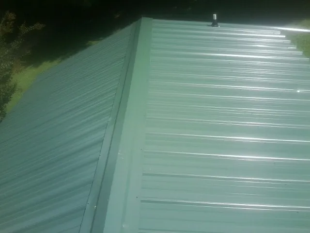 New green metal panels meeting at the ridge of a roof — Flat Roof Repair work by our crew in Bell Gardens