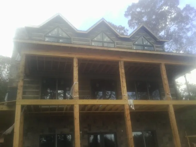 Dormers and porch framing on a large log home under construction — Roof Coating work by our crew in Bell Gardens