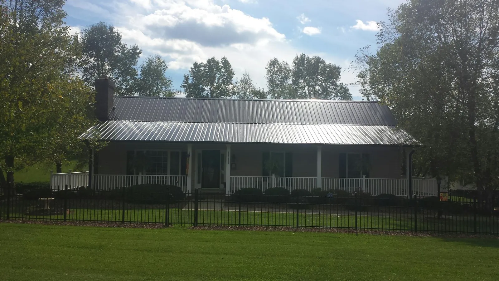 Gray metal roof on a brick ranch with a full width front porch — Gutter Guard Installation work by our crew in Bell Gardens
