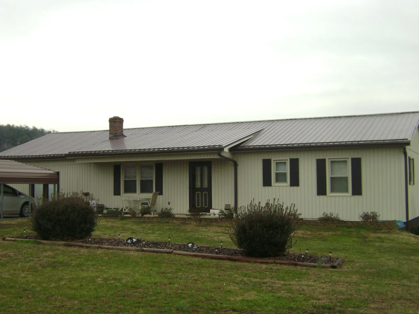 Brown metal roof on a cream sided ranch home with a brick chimney in Bell Gardens