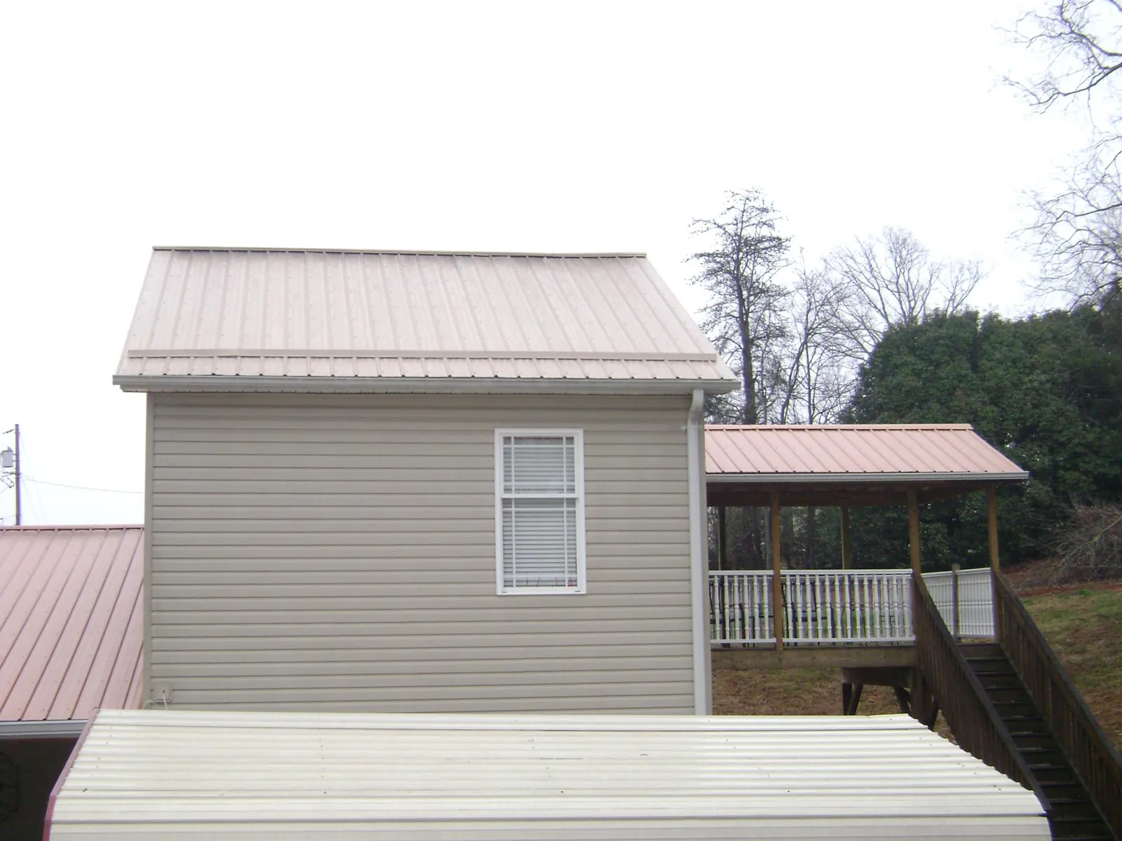 Tan metal roofs on a two story addition and attached porch, from a Roof Replacement job in Bell Gardens