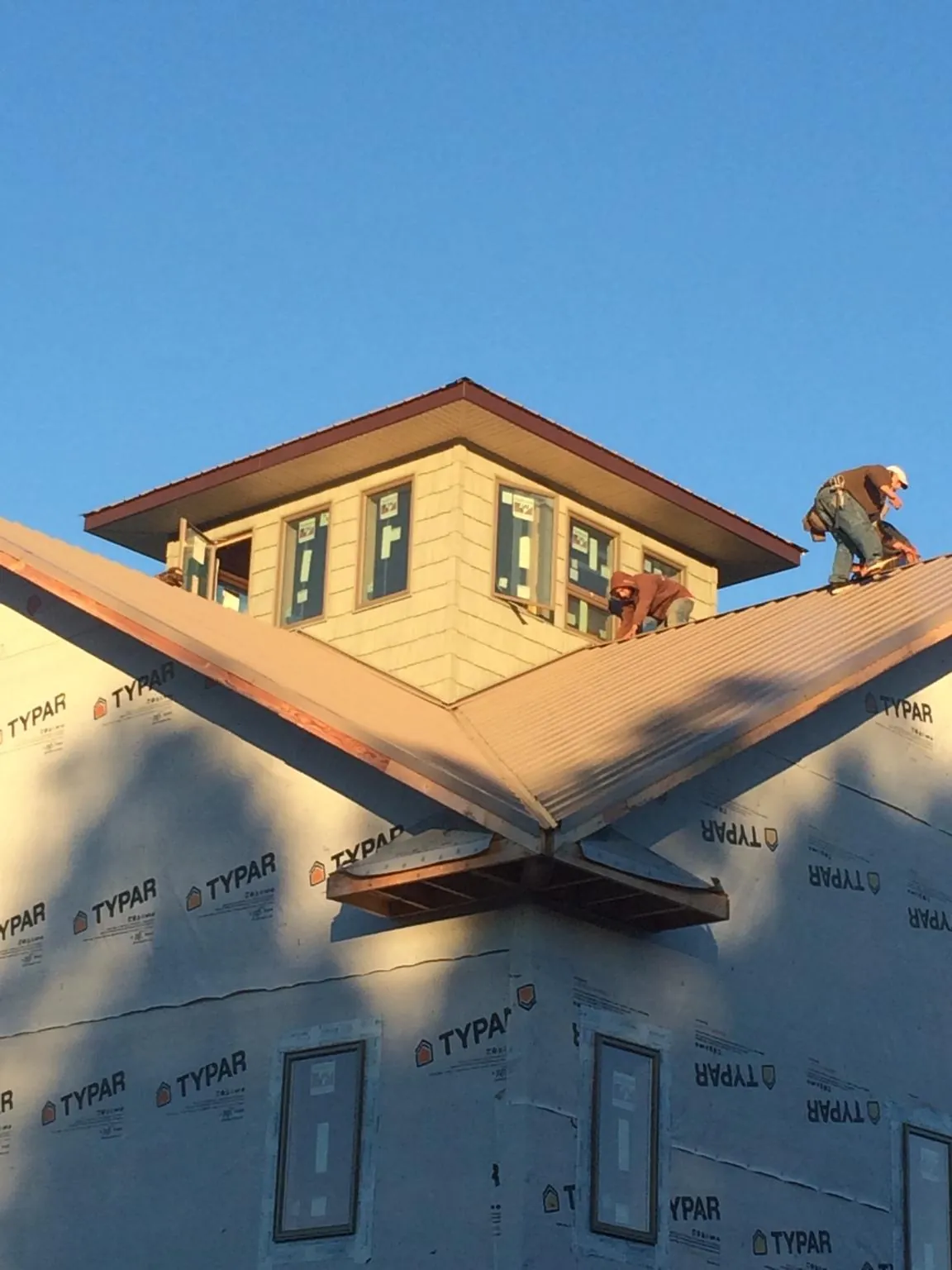 Roofers working around a rooftop cupola on a new metal roof at sunset — Roof Waterproofing in Bell Gardens by Roofing Brothers